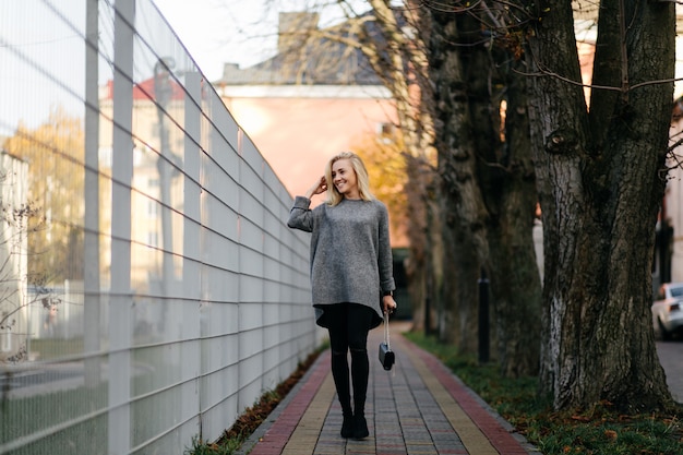 Sesión de fotos de la calle de la moda de elegante joven en una ropa gris