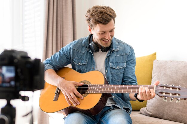 Sesión de guitarra de grabación masculino guapo en casa