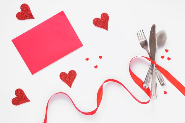 Set de cubiertos con corazones y papel rosa.