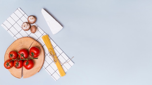 Foto gratuita seta; tomates rojos; pasta de queso y espaguetis con servilleta sobre fondo gris