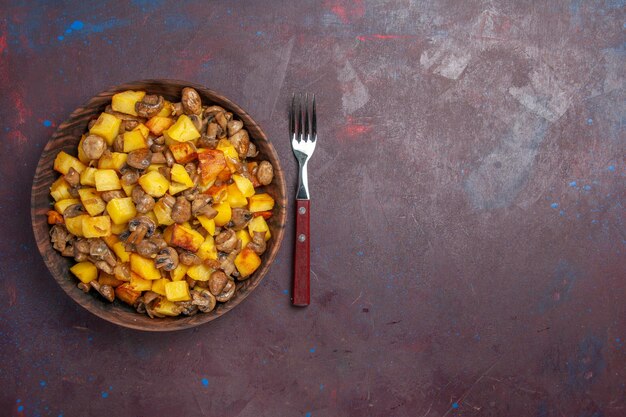 Setas de vista superior con patatas a la izquierda hay champiñones con patatas en un recipiente sobre la superficie oscura