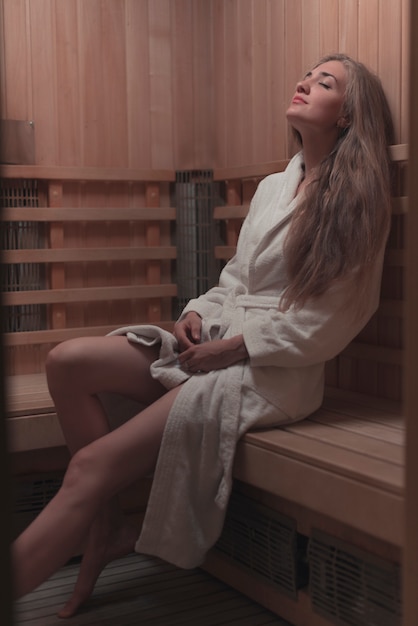 Foto gratuita sexy mujer joven relajante en sauna de madera