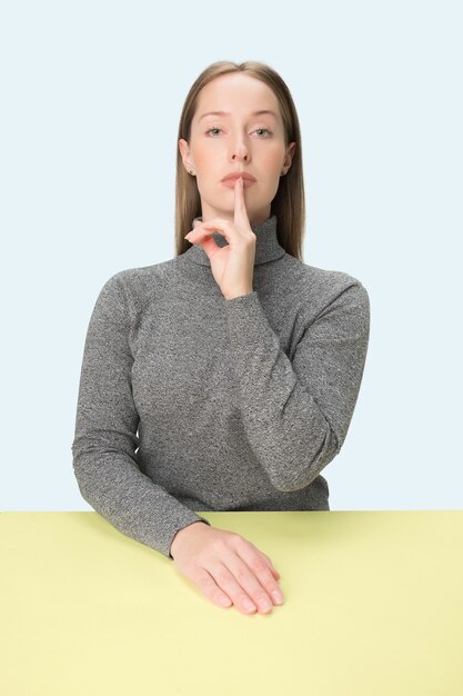 Shhhhh. Hermosa chica con maquillaje brillante y cabello rizado contando un secreto. Retrato de mujer que llama a alguien