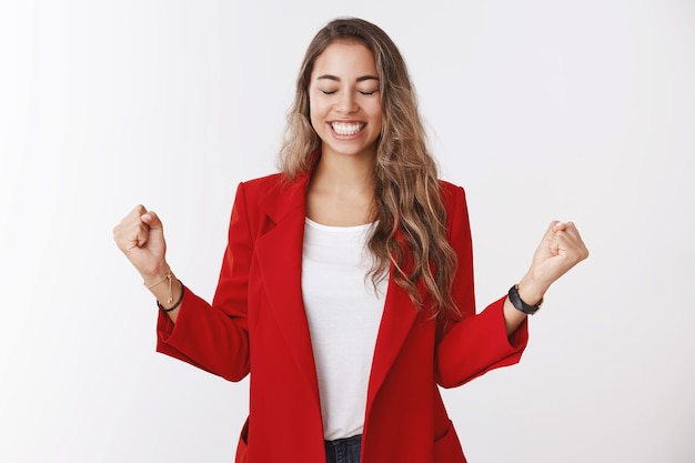 Sí, el éxito del sabor dulce gana. Retrato de mujer empresaria guapa feliz aliviada emocionada celebrando la victoria de la buena suerte, apretando los puños hacia los lados cerrar los ojos sonriendo, regocijándose ganador