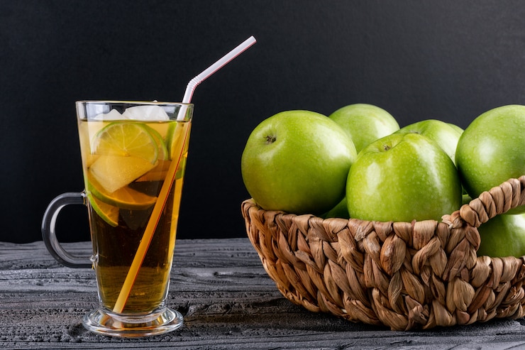 Photo Gratis side view green apples in beige straw basket and juice on gray wooden table and black