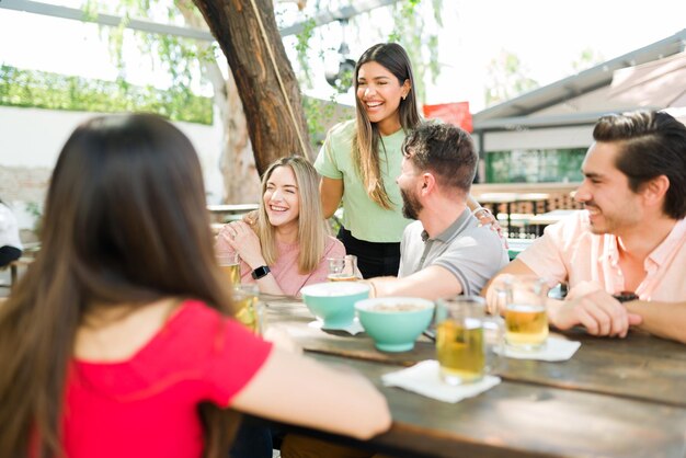 Siempre lo pasamos muy bien juntos. Feliz grupo de amigos divirtiéndose mientras beben cerveza y hablan en un bar restaurante al aire libre