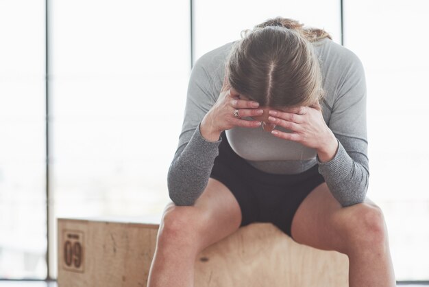 Se siente cansado. Deportiva joven tiene día de fitness en el gimnasio por la mañana