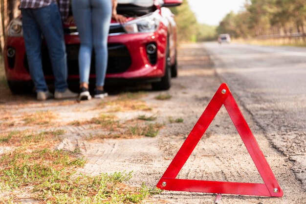 Signo de triángulo rojo en la carretera por problemas con el automóvil mientras viaja