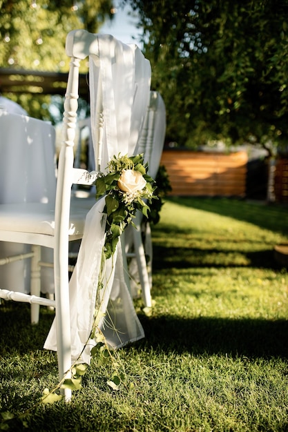 Silla blanca con ramo de rosas en el lugar de la boda al aire libre.