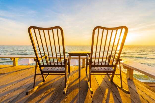 Silla y mesa de madera vacía en el patio al aire libre con hermosa playa tropical y mar