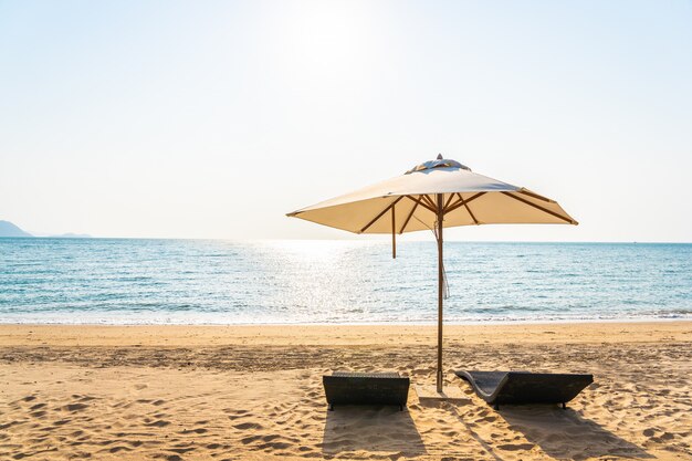 Silla sombrilla y salón en la hermosa playa mar océano en el cielo