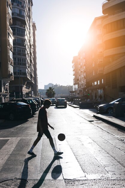 Silueta de un adolescente jugando al baloncesto en la calle en la ciudad