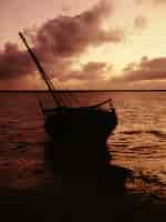 Foto gratuita silueta de un barco en una orilla cerca del agua bajo un cielo rosado en lamu, kenia