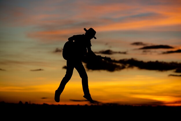 Silueta chica guitarrista en una puesta de sol