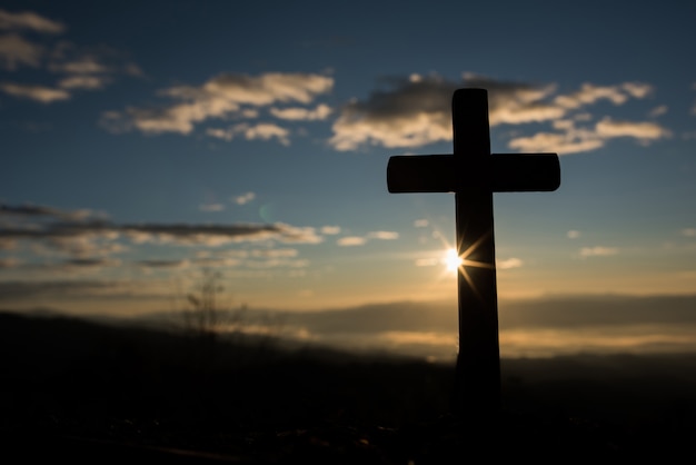 Silueta de cruz católica y amanecer.