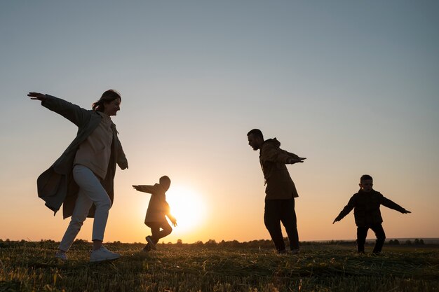 Silueta familiar de tiro completo divirtiéndose al atardecer