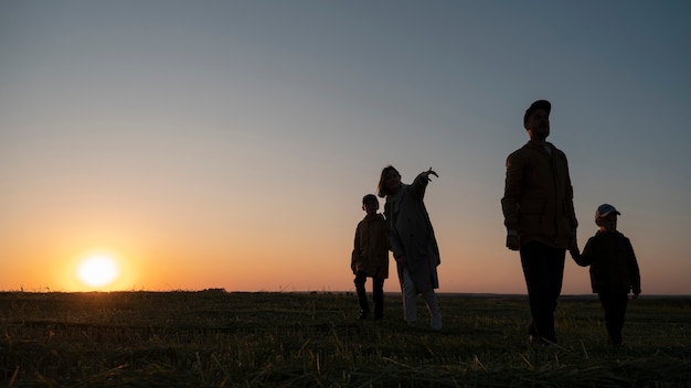 Silueta familiar de tiro completo divirtiéndose al atardecer