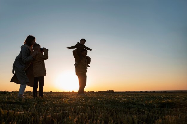 Silueta familiar de tiro completo divirtiéndose al atardecer