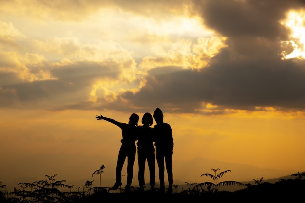 Silueta, grupo de niña feliz jugando en la colina, puesta de sol