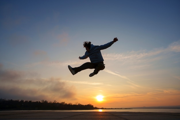 Foto gratuita silueta de hombre de tiro completo saltando al atardecer