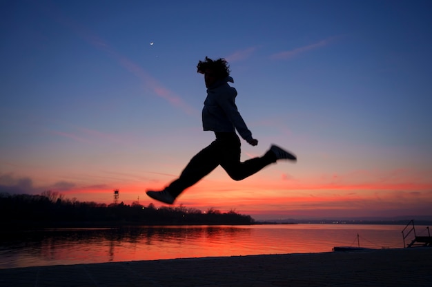 Silueta de hombre de tiro completo saltando al atardecer