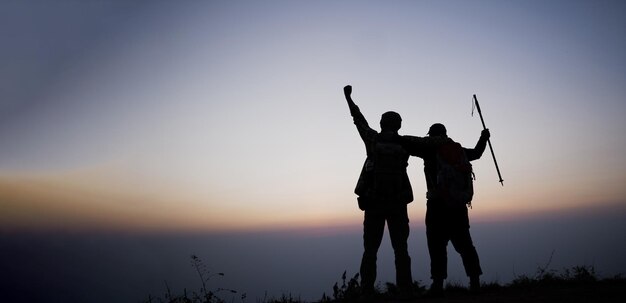 Silueta de hombres que animan a hacer senderismo abren los brazos al soporte del amanecer en la montaña Viajes Estilo de vida pasión por los viajes concepto de aventura vacaciones de verano al aire libre