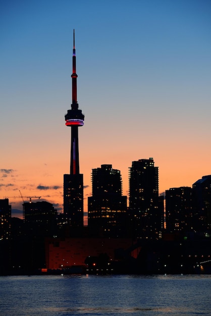 Silueta del horizonte de la ciudad de Toronto al atardecer sobre el lago con rascacielos urbanos.