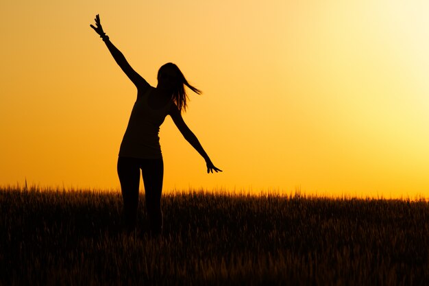 Silueta de joven feliz en el campo.