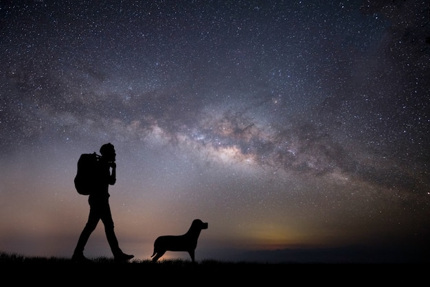 Silueta del joven mochilero caminando durante la puesta del sol.