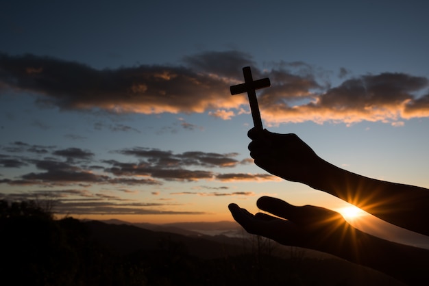 Silueta de mano sostenga cruz de dios