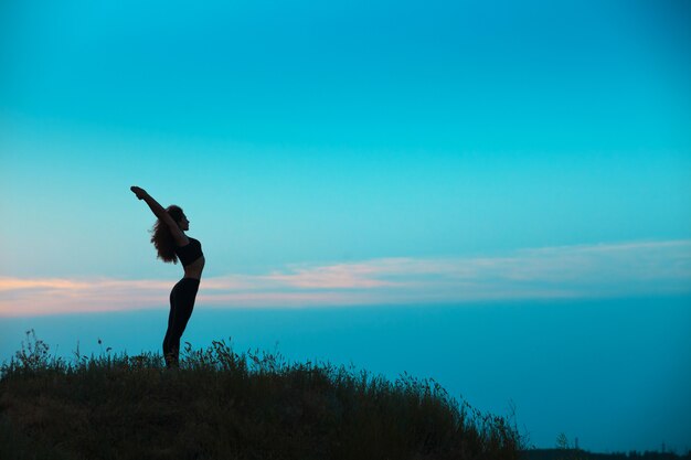 La silueta de una mujer joven practica yoga