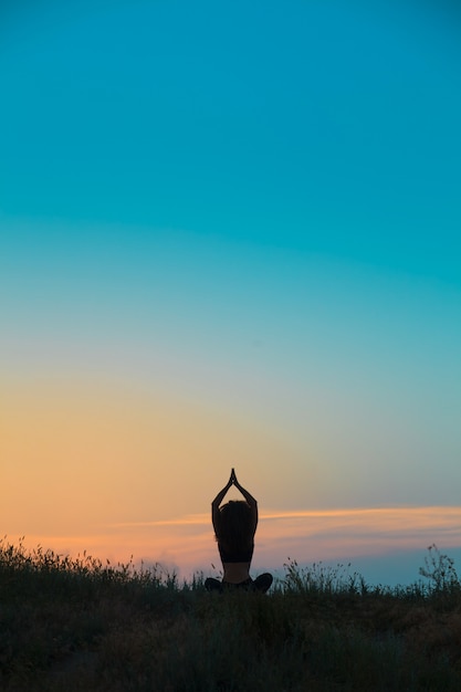 La silueta de una mujer joven practica yoga