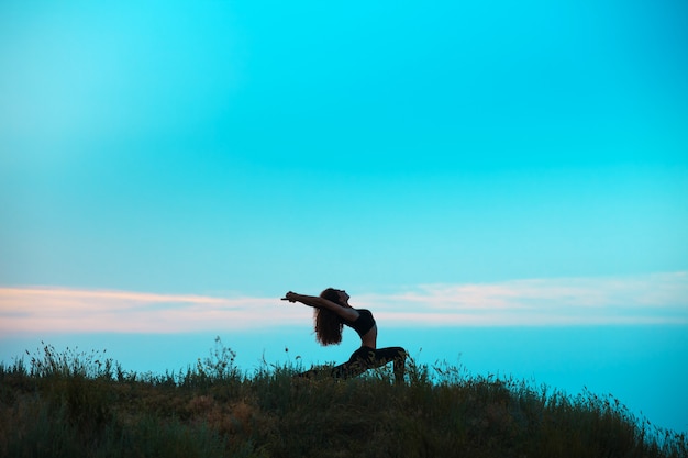 La silueta de una mujer joven practica yoga