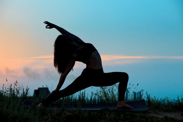 La silueta de una mujer joven practica yoga