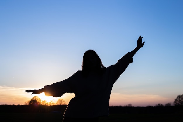 silueta, de, un, mujer, en, ocaso, en, un, campo, contra, el, cielo, vista trasera