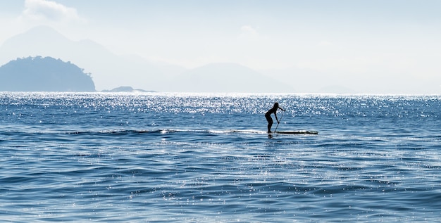 Silueta de una mujer surf de remo en el mar en Brasil