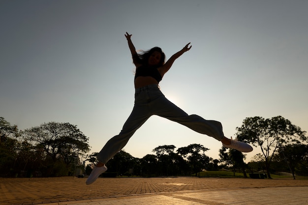 Foto gratuita silueta de mujer de tiro completo saltando al atardecer