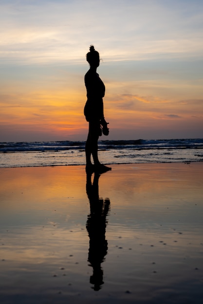 Silueta de una niña de pie en el agua en una playa