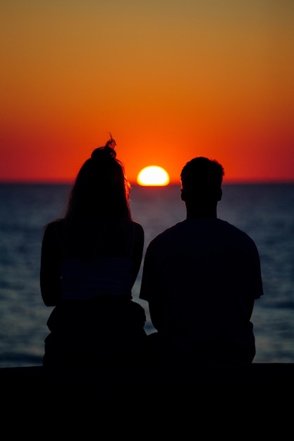 Silueta de una pareja disfrutando de la hermosa puesta de sol en la orilla del mar
