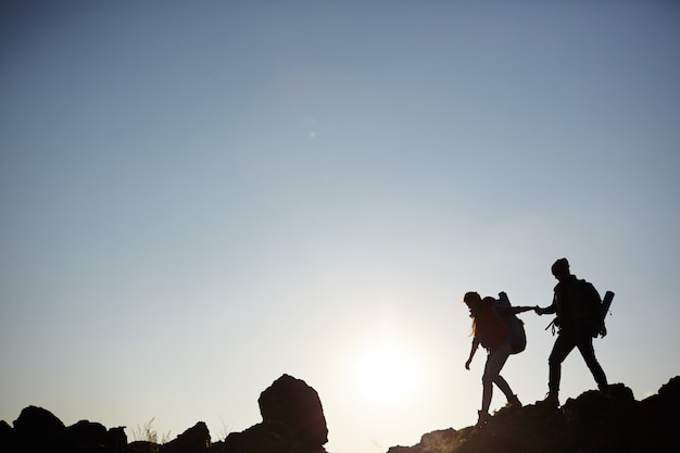 Silueta de pareja escalar montañas