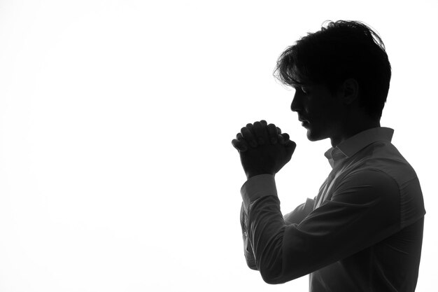 Silueta de persona masculina en ropa blanca en pose de oración sombra fondo blanco