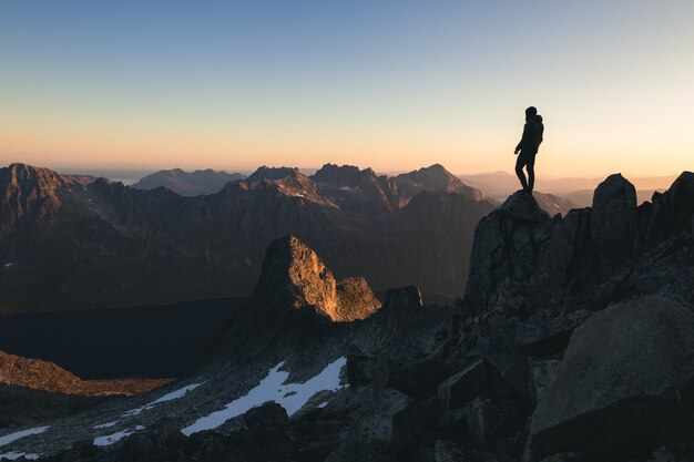 Silueta de una persona de pie en la cima de una colina bajo el hermoso cielo colorido de la mañana