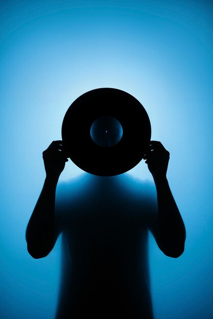 Silueta de una persona sosteniendo un disco de vinilo