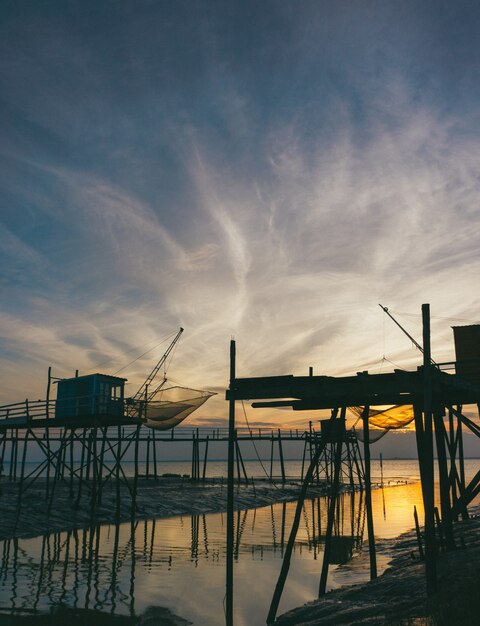Silueta de soportes de madera cerca del mar durante la puesta de sol