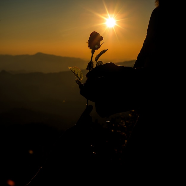 La silueta de la tenencia de los pares se levantó en la colina en el horizonte del tiempo de la puesta del sol en fondo