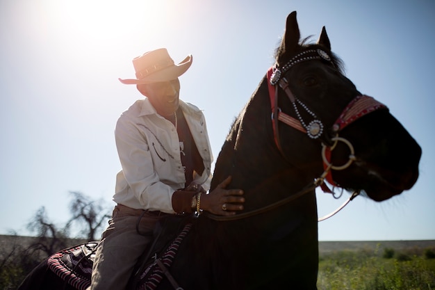 Silueta de vaquero con caballo contra luz cálida