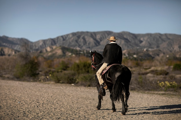 Silueta de vaquero con caballo contra luz cálida