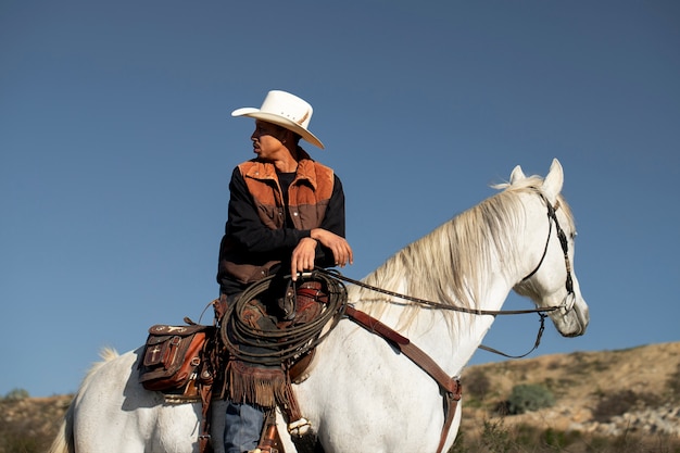 Silueta de vaquero con caballo contra luz cálida