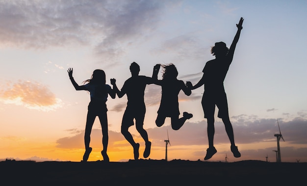 Foto gratuita siluetas de amigos felices saltando al atardecer