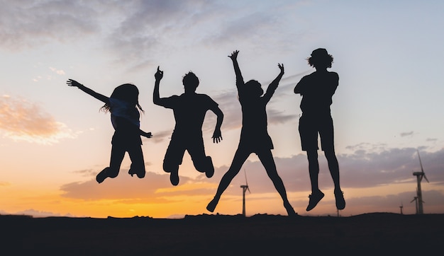 Siluetas de amigos felices saltando al atardecer